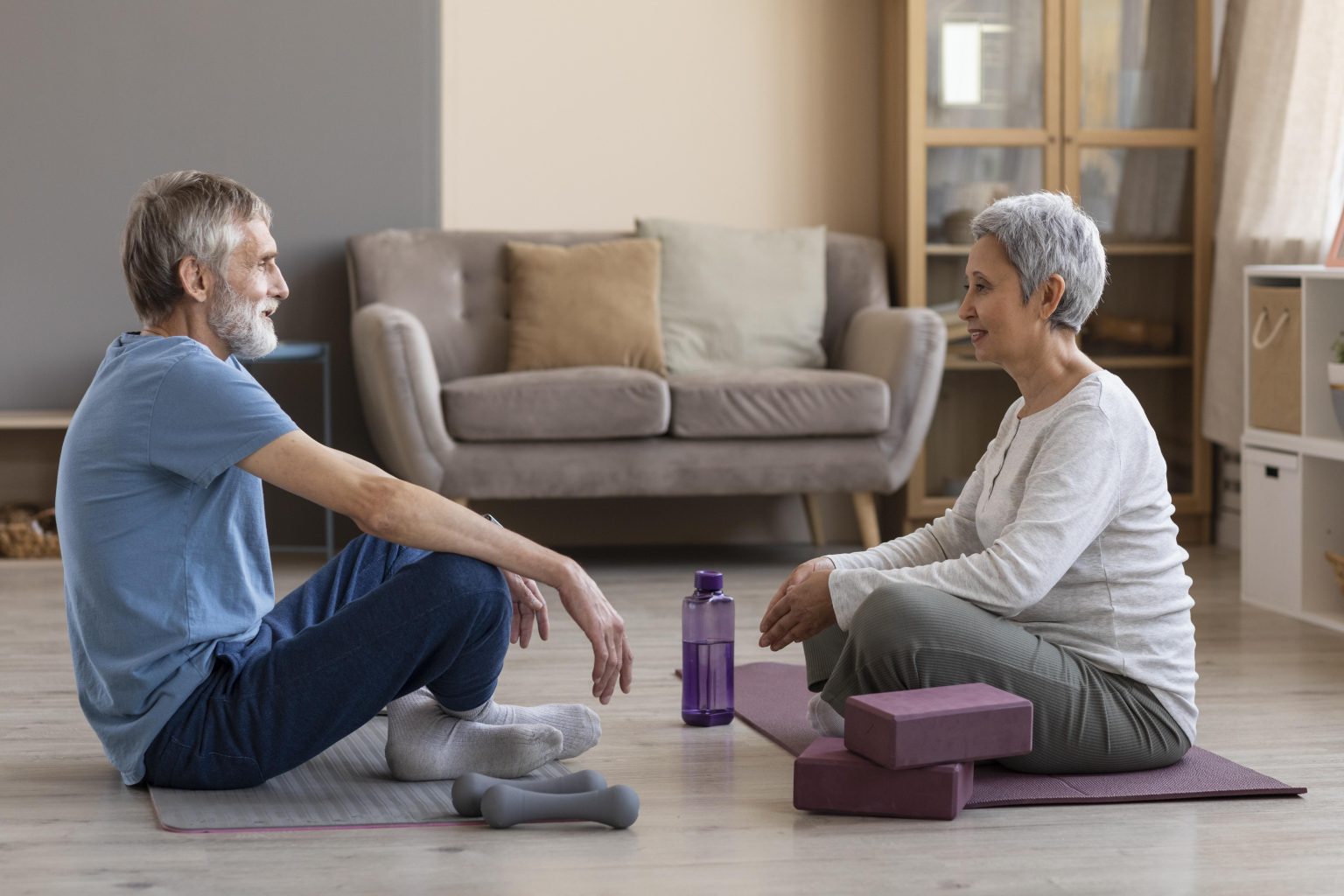 Dos personas mayores realizando ejercicio en casa